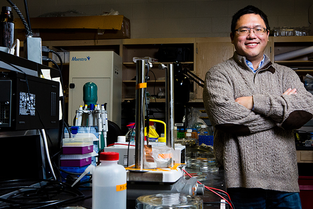 A photo of Xiaocheng Jiang standing by a table in his lab.