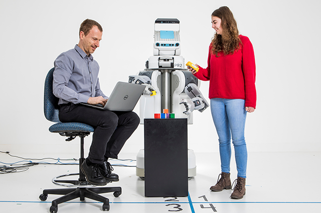 Professor Matthias Scheutz and Ph.D. candidate Theresa Law looking at large robot together in the HRI Lab