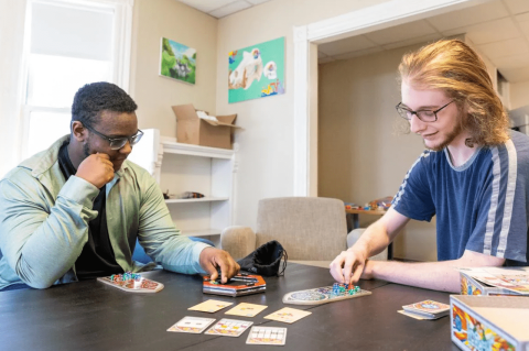 Students play a card game at the house.