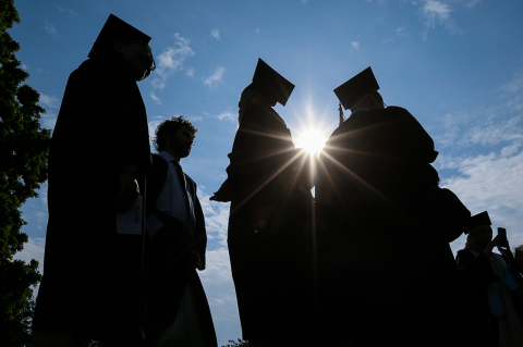 Silhouettes of graduating students in caps and gowns.