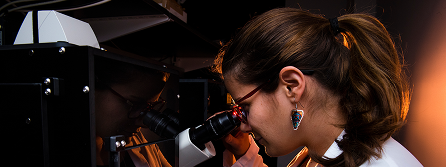 Female student looking through microscope.