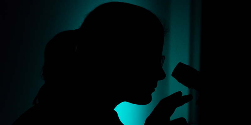 Silhouette of a woman looking in a microscope.