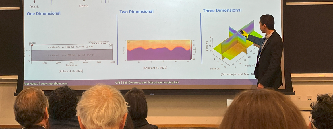 A speaker discusses a powerpoint slide at the symposium.