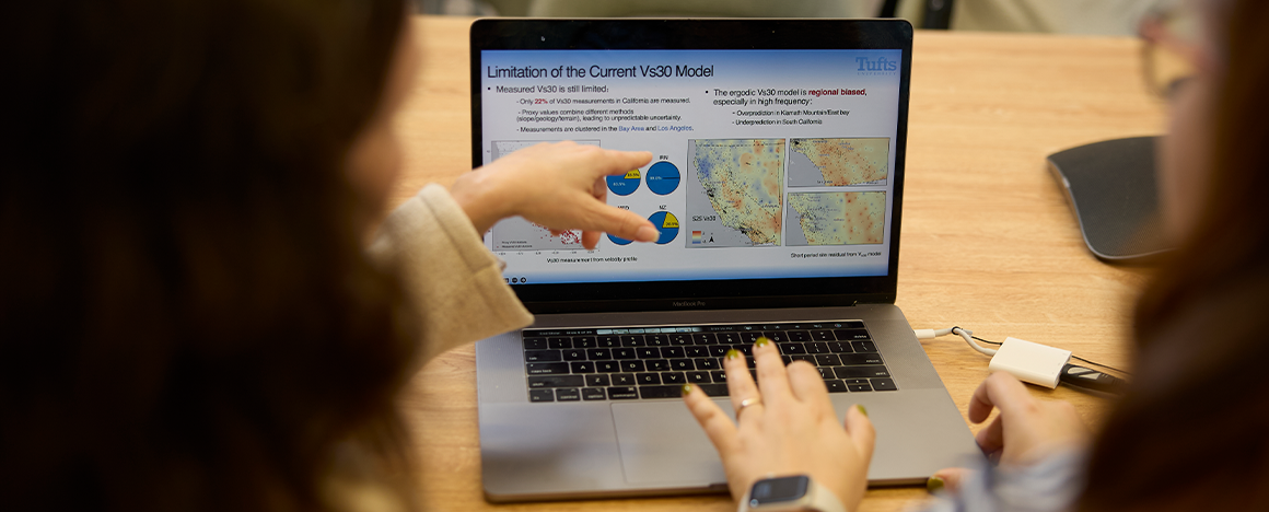 Two researchers point at graphs on a laptop