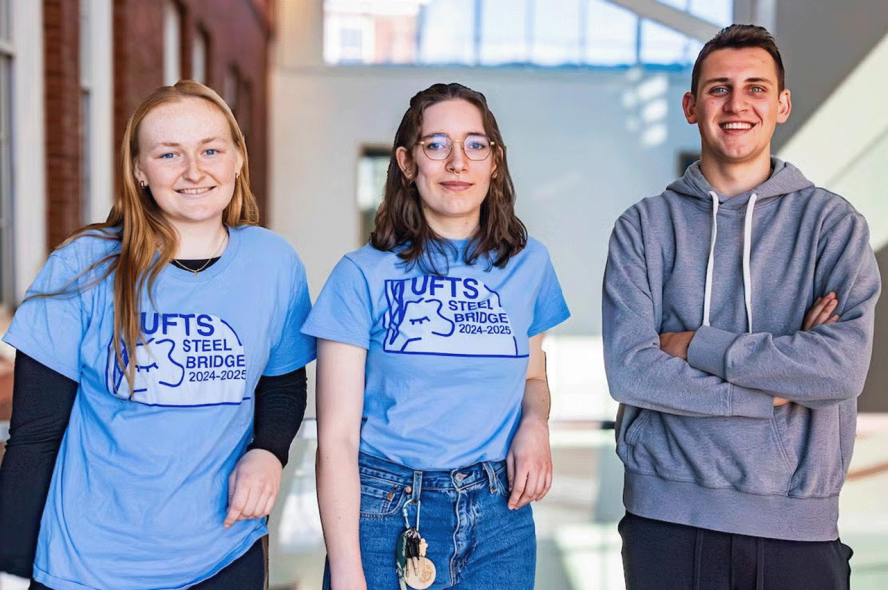 Three students stand in a brightly lit building