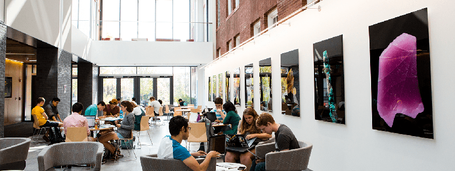 Students studying at tables and chairs in atrium.