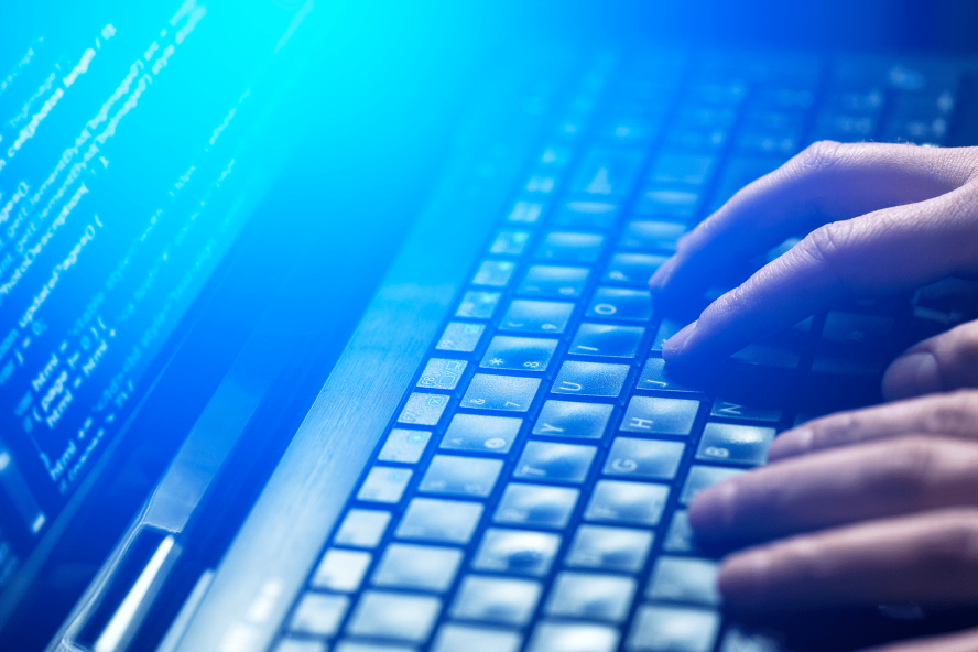 A person typing on a laptop keyboard.