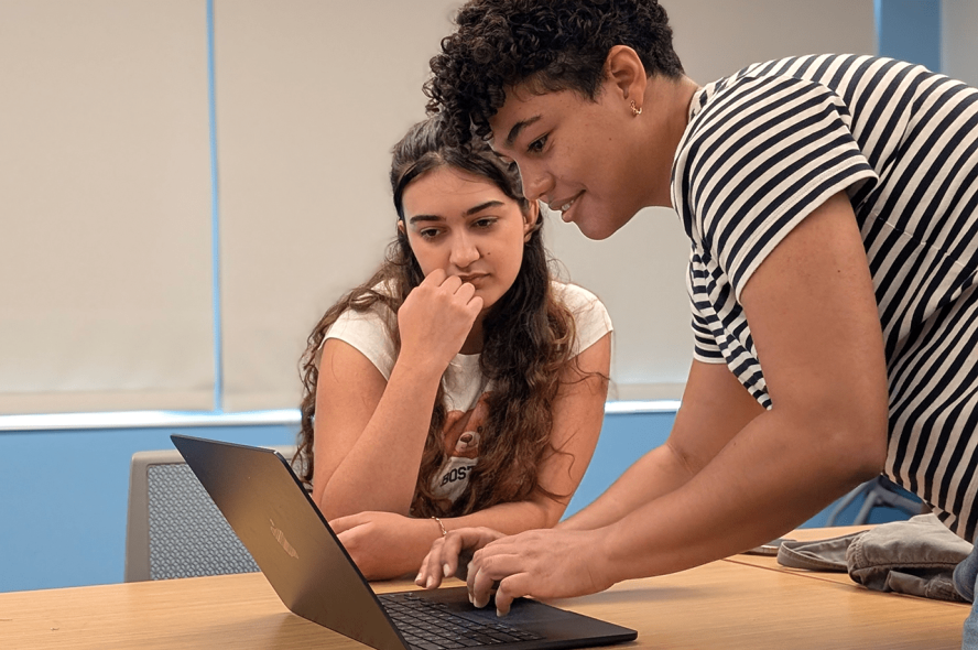 Two students work together at a laptop.