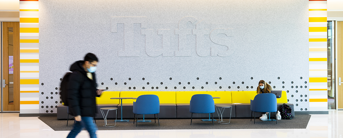 A student walks past the Tufts sign in the Joyce Cummings Center