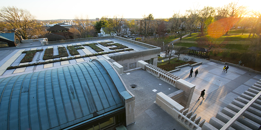 Students walking on the Tisch Library patio at sunset