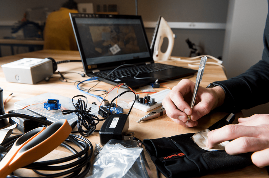 A desk with a laptop, tools, and a pen.
