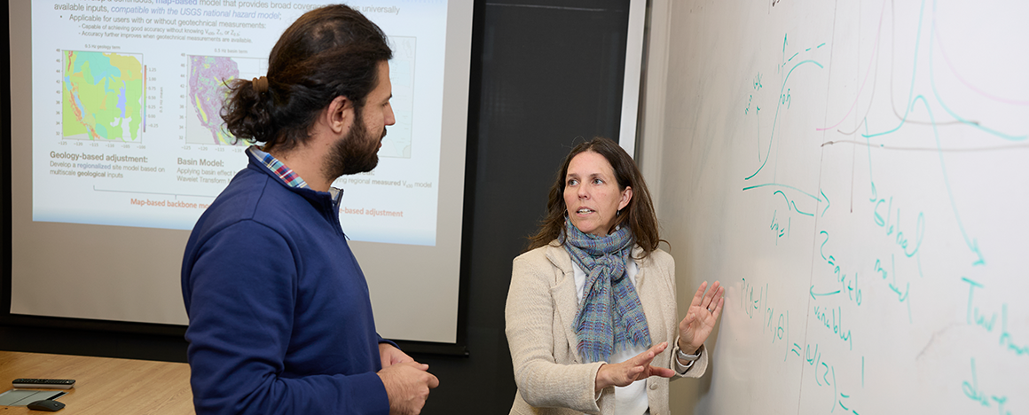 Laurie Baise (right) gestures at the white board as she talks with Hooman Shirzadi (left).