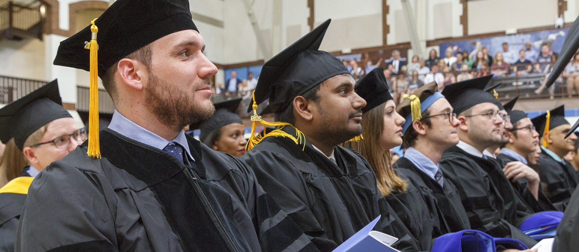 Graduate students seated in Cousens Gymnasium at the 2019 ceremony