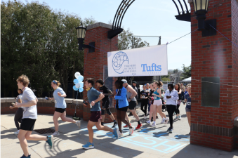 Runners at the EWB Fred Berger 6K begin the race under a Tufts Engineers Without Borders banner. 