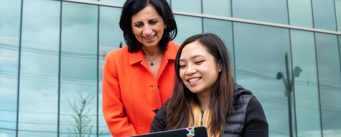 Professor Soha Hassoun looks over computer science student Yan Zhou Chen's shoulder at a laptop screen. 