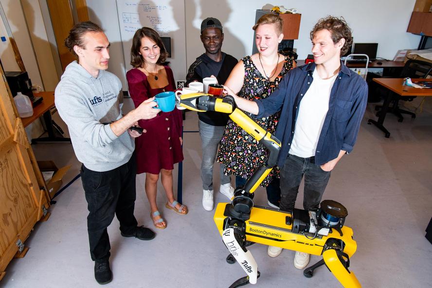 Students share a toast with the Boston Dynamics robot in the Human Robot Interaction Laboratory