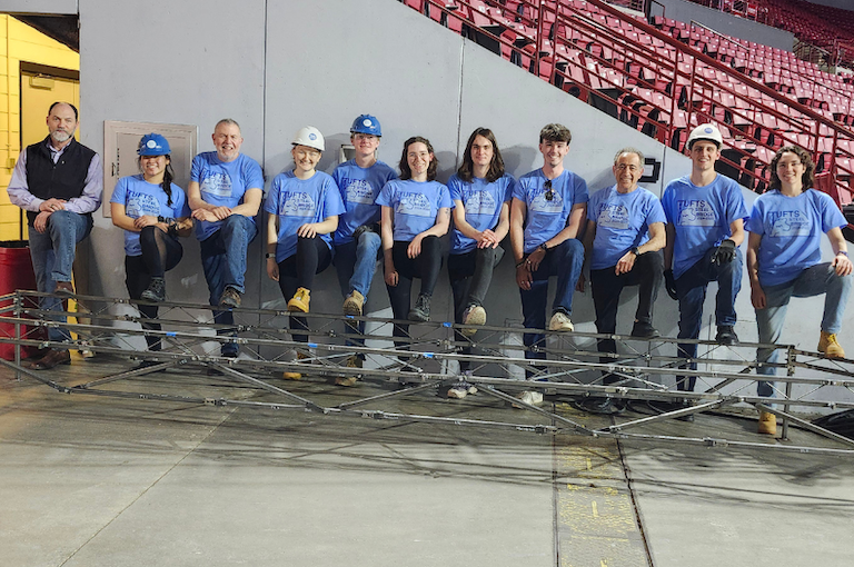 a group of people in blue shirts posing for a picture at the 2025 Northeast Regional American Institute of Steel Construction (AISC) Student Steel Bridge Competition