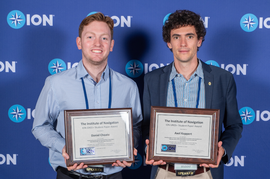 two men holding awards in front of a blue wall