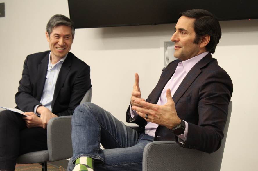Ted Myles (right) gestures with his hands as he speaks. Kyongbum Lee (left) smiles as he listens to Ted speaking. 