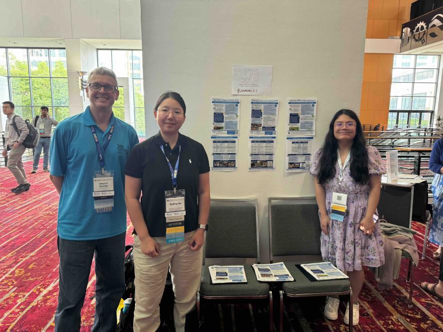 A man and two women attending conference posing with informational hand outs