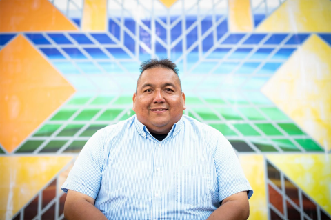 Vernon Miller, inaugural director for the newly established Tufts Indigenous Center, poses for a portrait in front of “Wakpa”, a mural installation by Indigenous artist Erin Genia.