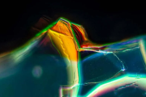 An extreme closeup of a piece of glass with multiple colors. 