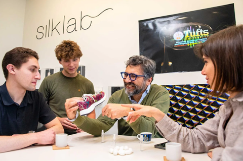 Fiorenzo Omenetto, director of Silklab, and students examine a prototype of a “chameleon” sneaker. The shoe’s upper sports a pattern made of silk inks, the color of which can be changed by spraying a liquid on it.
