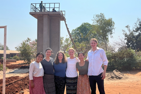 Students standing in front of a water tower in Malawi. From left to right – Kana Suzuki, Melanie Sun, Julia Zelevinsky, Katie Casey, Natasha Wan, Max Harrington