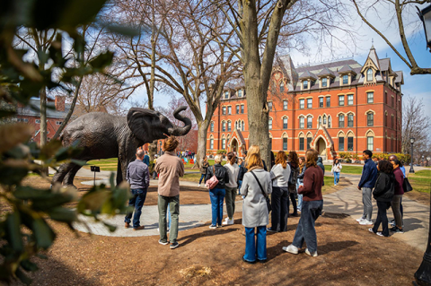 A group of people standing near the Jumbo the elephant statue on the Tufts Medford campus.