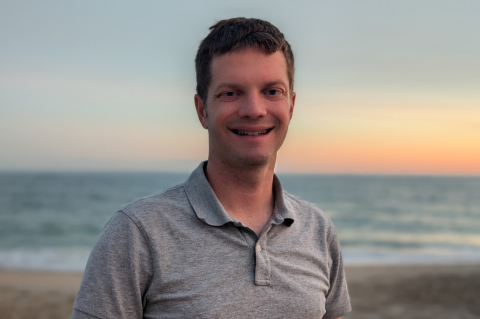 Michael C. Hughes standing in front of the ocean at sunset