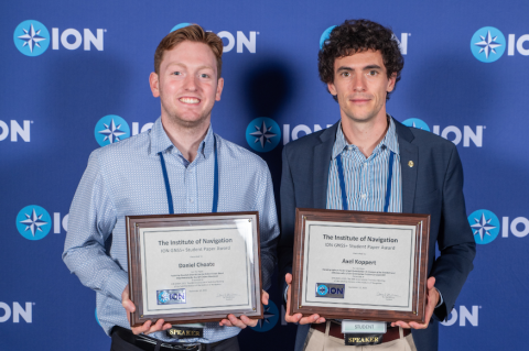 two men holding awards in front of a blue wall