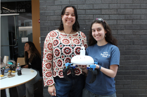 Students posing with a small white robot with four legs