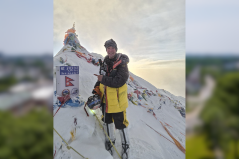 Tyler Andrews posing on the top of Mount Everest