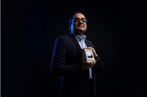 Sameer Sonkusale posing with small white device in front of a dark background