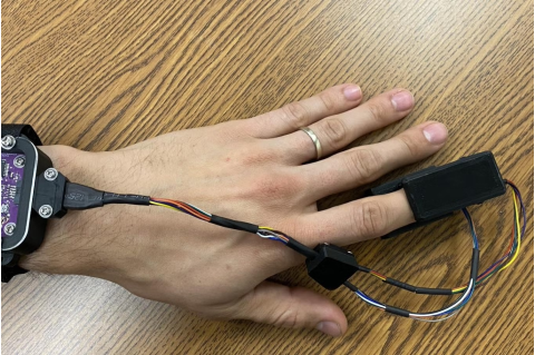 Close-up photo of a hand with a small monitoring device on pointer finger
