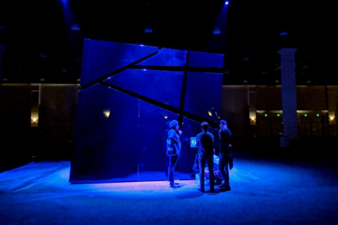 Distance shot of people standing on a stage in blue light