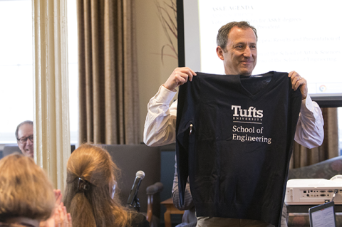Dean Jim Glaser holds up the School of Engineering sweater that he wore as part of a bet with Dean Jianmin Qu