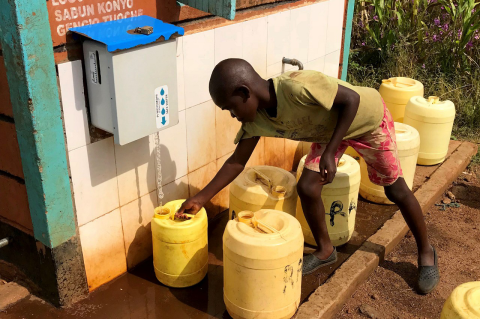 A young boy gets water from a neighborhood spigot in Uganda. A Tufts study shows low-cost water purification, which can save lives from waterborne diseases, does not harm beneficial bacteria in children’s guts