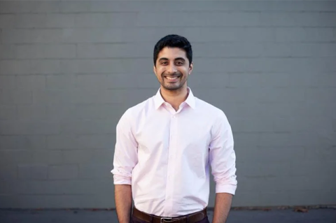 Ryan Pandya, E13, standing in front of a gray brick wall