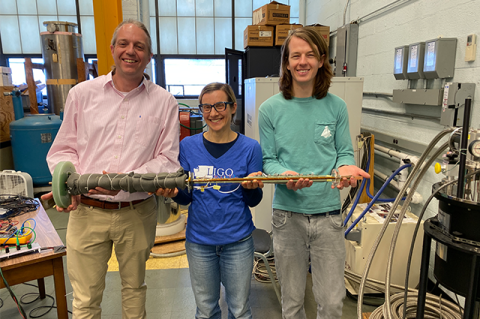 From left to right: Associate Professor Rob White, Associate Professor Luisa Chiesa, and PhD student Peter Moore, all of the Department of Mechanical Engineering. They are in the lab holding a long metal device used for their experiments.