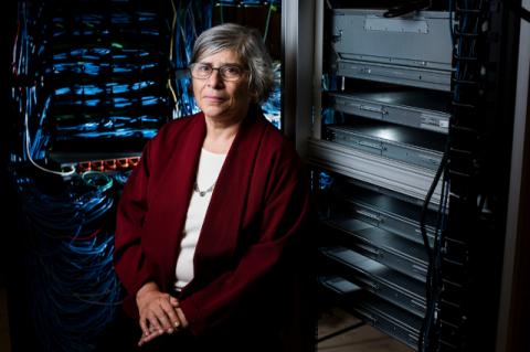 A woman sits in a dark computer lab