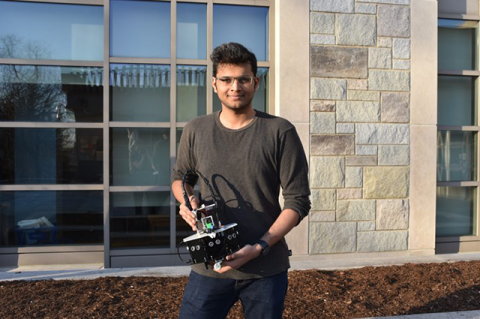 A member of the Tufts Robotics Team holding a small robot.