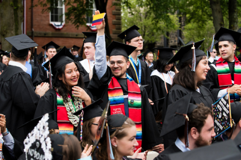 A student waves a Colombia flag while wearing a graduation cap and gown.