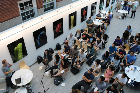 An overhead image of people sitting and watching a presentation