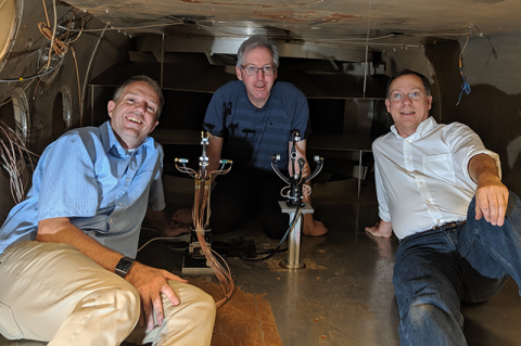Three men with sonic anemometer prototypes in wind test tunnel